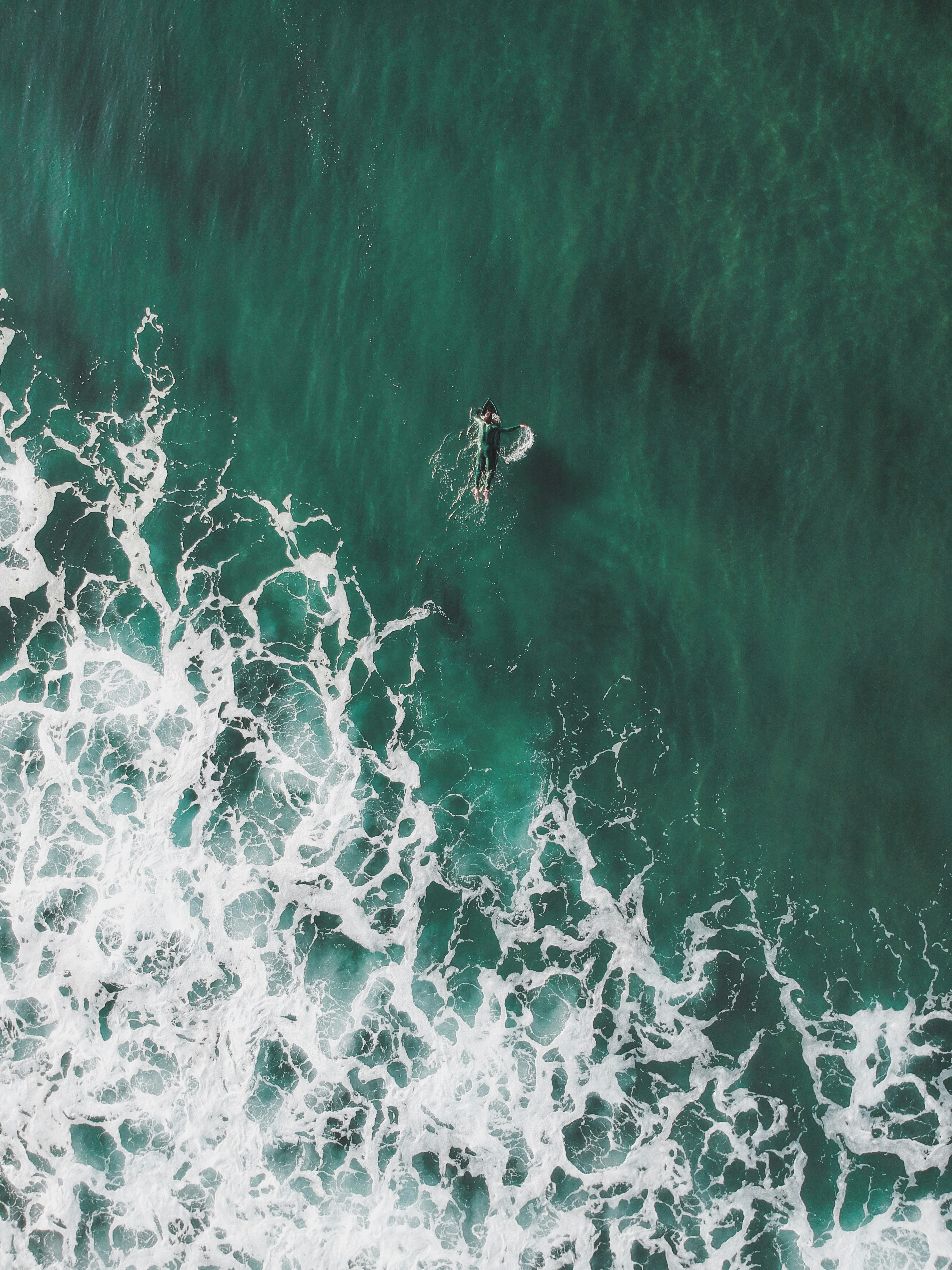 aerial view of man swimming into the ocean